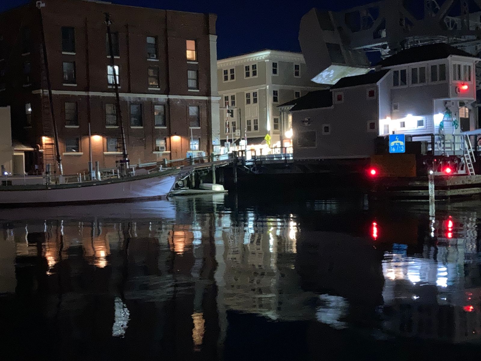 Mystic bascule bridge reflected in still harbor water at night